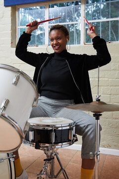Black woman with short hair playing drums