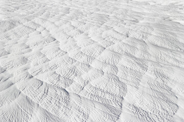 Textured effect of waves on surface of gray-white stone. Pamukkale travertine surface in Turkey.