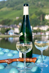 White quality riesling wine served on old bridge across Mosel river with view on old German town in sunny day