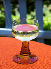 White quality riesling wine served in yellow swirl wine glass on outdoor terrace in Mosel wine region, Germany