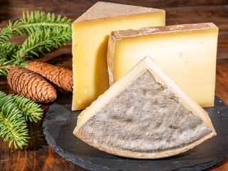 Cheese collection, French cow cheese comte, beaufort, abondance, tomme de savoie and fir cones