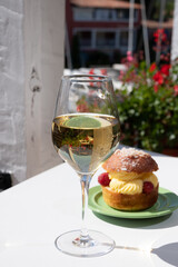 Tarte tropezienne or La Tarte de Saint-Tropez - dessert pastry consisting of filled brioche with cream and fresh berries.and glass of white wine