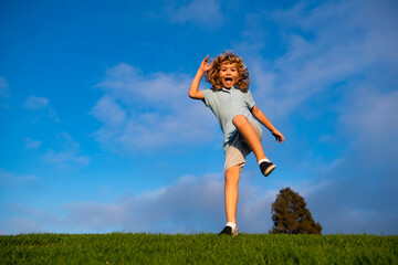 Caucasian boy in a park running and smiling. Happy kid laughing. Emotion face joy child. Joyful, funny spring, summer day, outdoors. Sky background, banner with copy space.