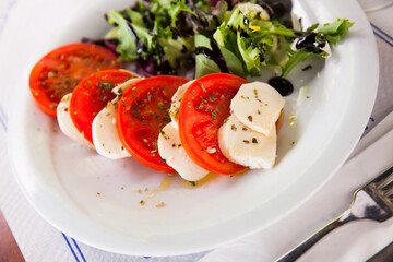 Fresh italian caprese salad with mozzarella and tomatoes on white plate. High quality photo