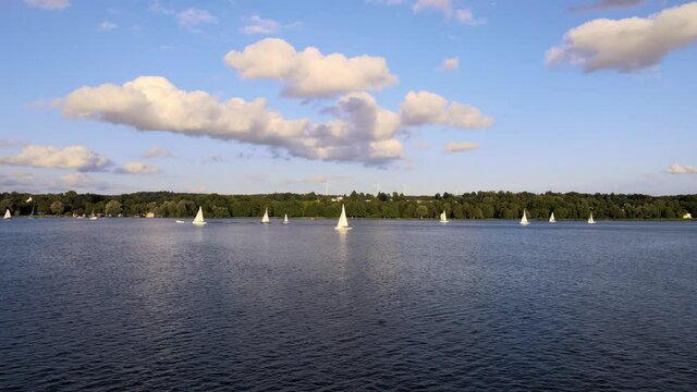 Sailboat on lake Starnberg. Munich residents and vacationers sail and relax on the idyllic mountain lake in Bavaria. Aerial view from drone