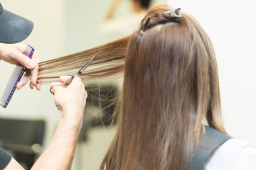 Naklejka premium ヘアサロンで女性の髪の毛をカットするスタイリストの手元