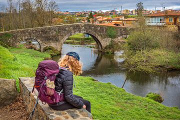Pilgrim Girl Looking at Medieval Stone Bridge Puente San Xoan in Furelos along the Way of St James...