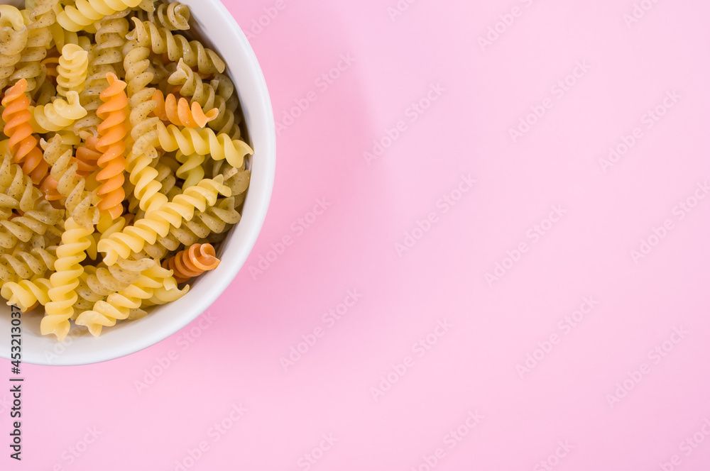 Wall mural Top view of little white pottery with colored pasta isolated on