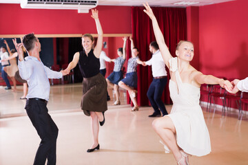 Active young dancing couples enjoying latin dances in modern studio