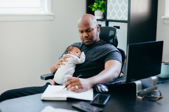 Black dad with newborn working from home