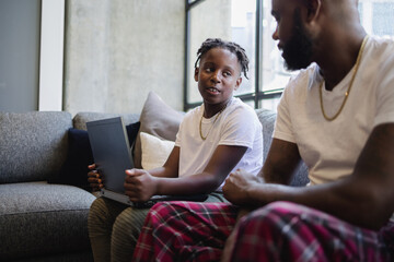 Father and son with laptop sitting on sofa in living room