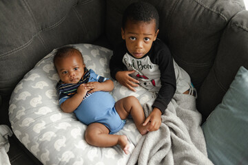 Black boys, siblings, sitting and laying on sofa