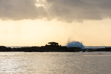 Vista do nascer do sol no mar colidindo com pedras no litoral