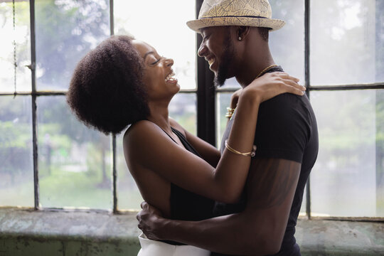 Young couple standing by window and embracing