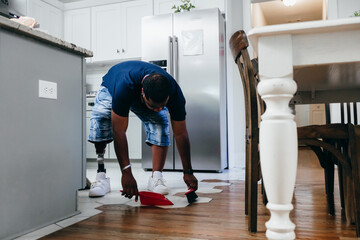 African American man doing chores around the house, sweeping, disabled