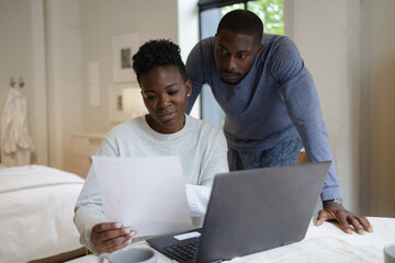 Couple reading document and using laptop