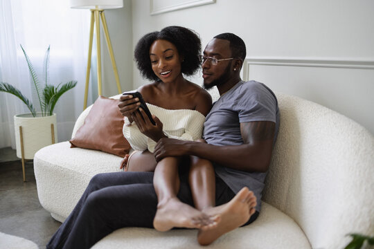 Couple sitting on sofa and using smart phone