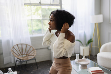 Young woman fixing hair in living room