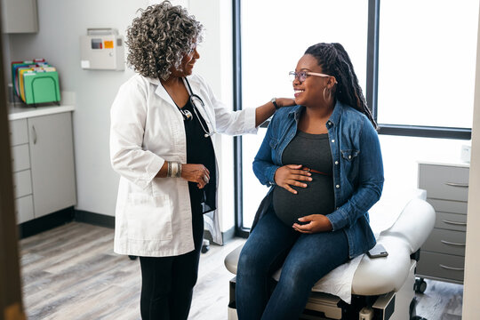 Black female doctor speaks with female pregnant patient