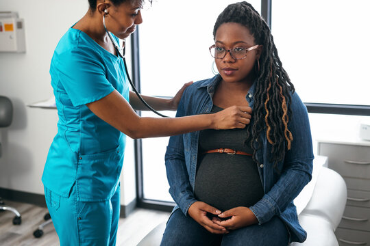 Black woman nurse checks vitals of pregnant patient