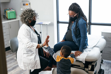 Female doctor speaking with patients, Black mother and toddler, connectedness