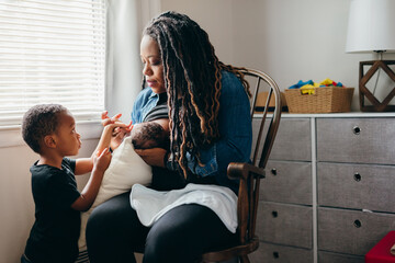 Black mom breastfeeds baby and talks to sibling