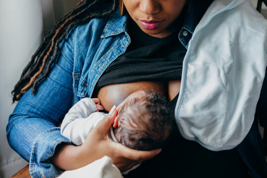 Black woman breastfeeding child at home
