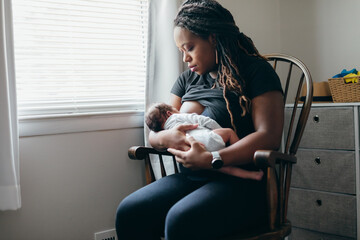 Black woman breastfeeding child at home