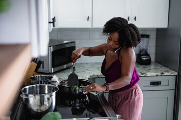Black woman cooking at talking on phone, multitasking 
