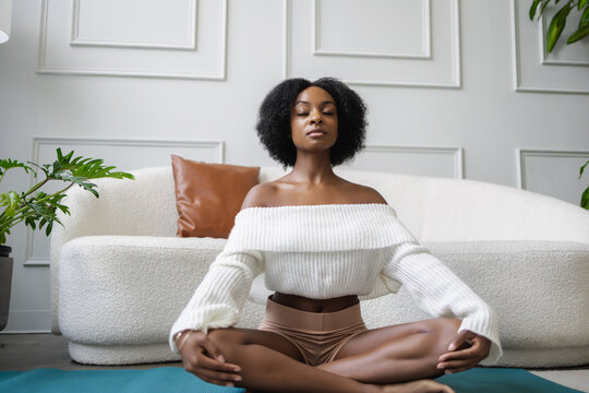 Young Black Woman Meditating In Living Room