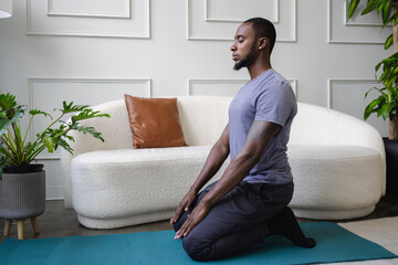 Young man meditating in living room