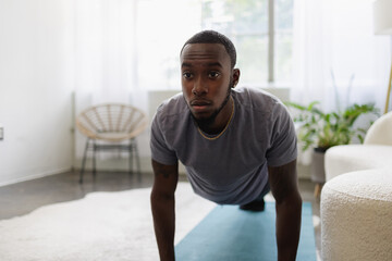 Young man doing plank in living room