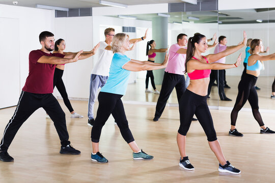 Positive people of different ages studying zumba dance elements in dancing class