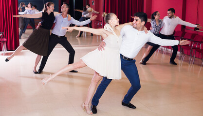 Group of happy people dancing samba in couple in dance class. - obrazy, fototapety, plakaty
