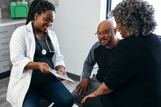 Black pregnant doctor consulting with senior patients 