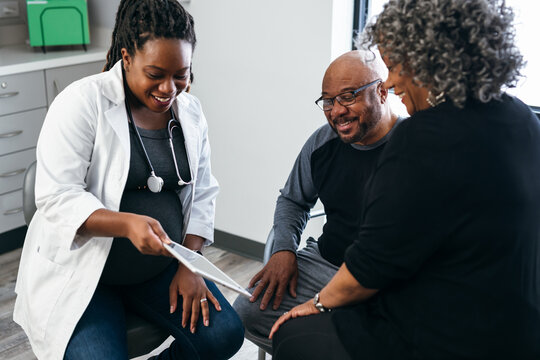 Black pregnant doctor consulting with senior patients 