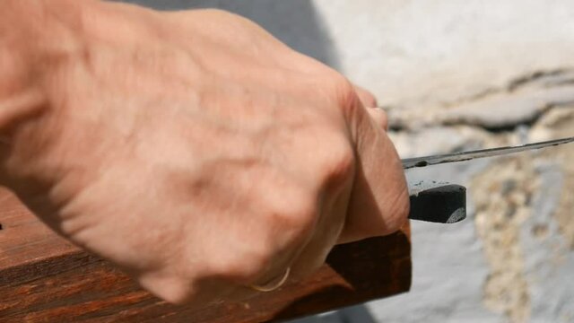 Close-up of beautiful man's hands sharpening a knife with a whetstone close-up