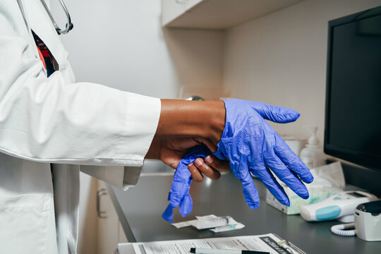 Black Doctor using rubber gloves, close up of hands