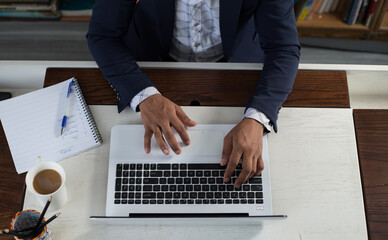Unrecognizable person. Top view of a businessman using laptop computer in the office. Conceptual business portrait of hands on the keyboard. 