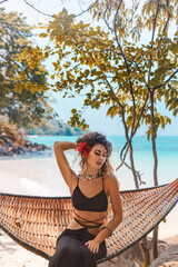 Beautiful young fashionable woman in black dress posing at the beach