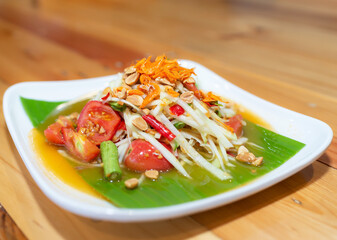 Green Papaya Salad (Som tum Thai) on wood table, Traditional spicy Thai food. Selective focus