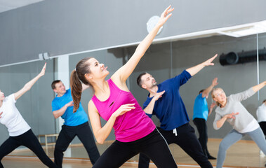 Fototapeta na wymiar Young smiling woman practicing vigorous lindy hop movements in dance class