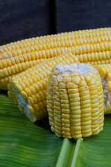 Fresh corn in bamboo basket with wooden chopping board, closeup