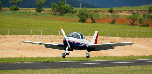 Fototapeta na wymiar Light aircraft landing on aerodrome runway on sunny day.