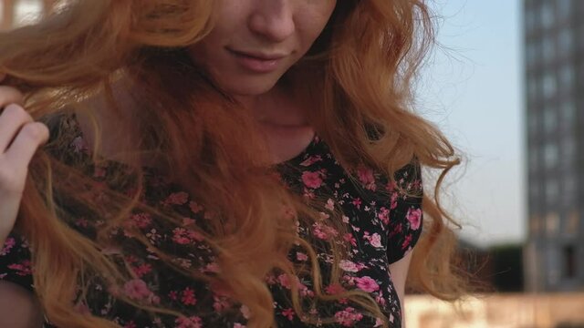 Red hair on wind. Head and shoulders shot of the ginger haired lady plays with her lonf wavy red hair outside