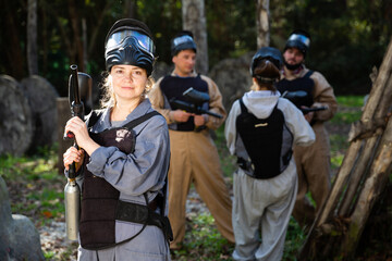 Portrait of girl in full gear posing with shooting gun at paintball shooting range