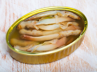 Seafood appetizer. Open can of preserved natural molluscs razorshell (ensis) on wooden table