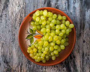 Green grapes lined with a slide on a clay plate close-up