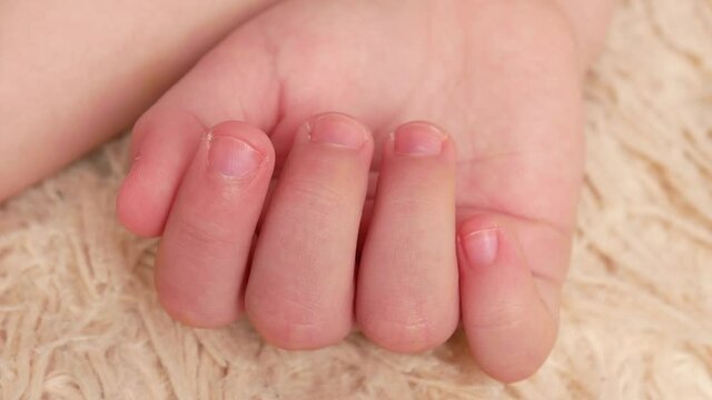 Close-up of a sleeping baby's hand moving the fingers