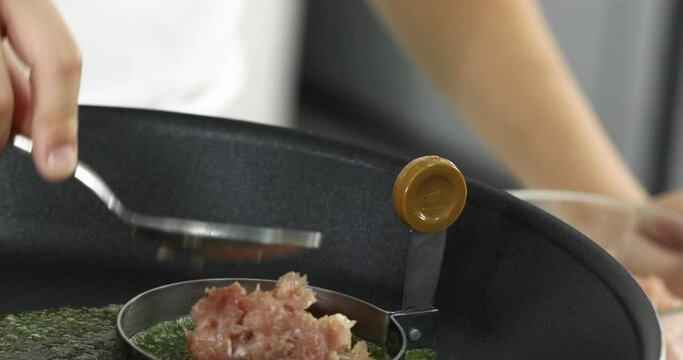 Hand putting raw pork into mold on hot gas stove with melt butter for testy and good smell prepare ingredients for making homemade burger.